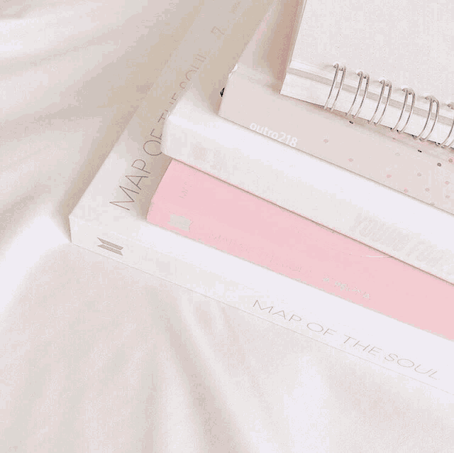pink and white books stacked on top of each other with one titled map of the soul