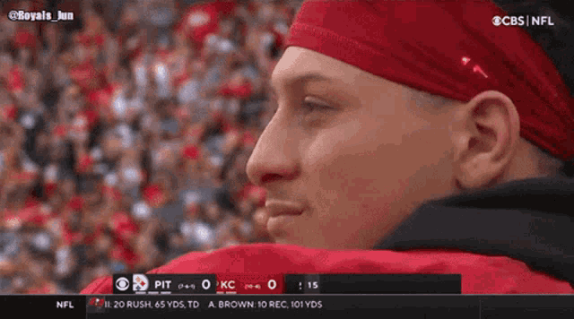 a man in a red headband is watching a football game on cbs