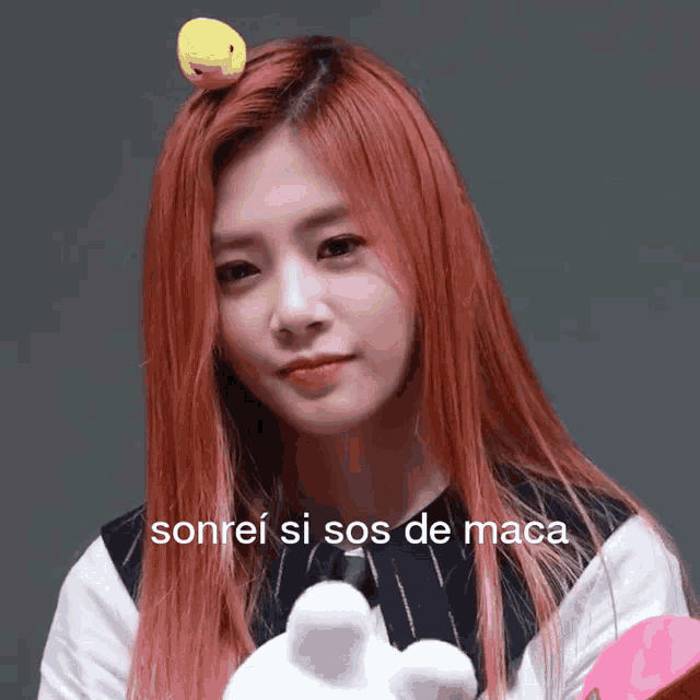 a woman with red hair has a stuffed animal on her head and the words sonrei si sos de maca are below her
