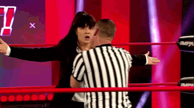 a referee is talking to a woman in a suit in a ring