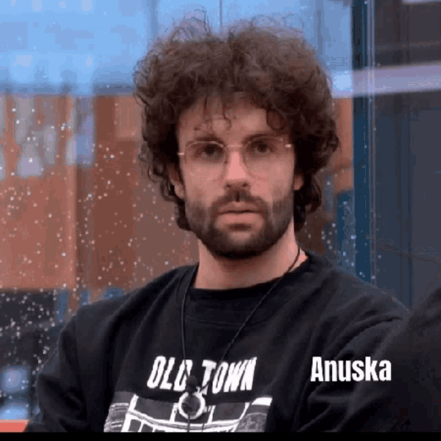 a man with curly hair and a beard is wearing a black shirt that says old town