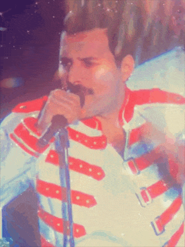 a man singing into a microphone with a red and white uniform