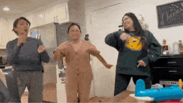 three women are dancing together in a living room in front of a toy airplane .