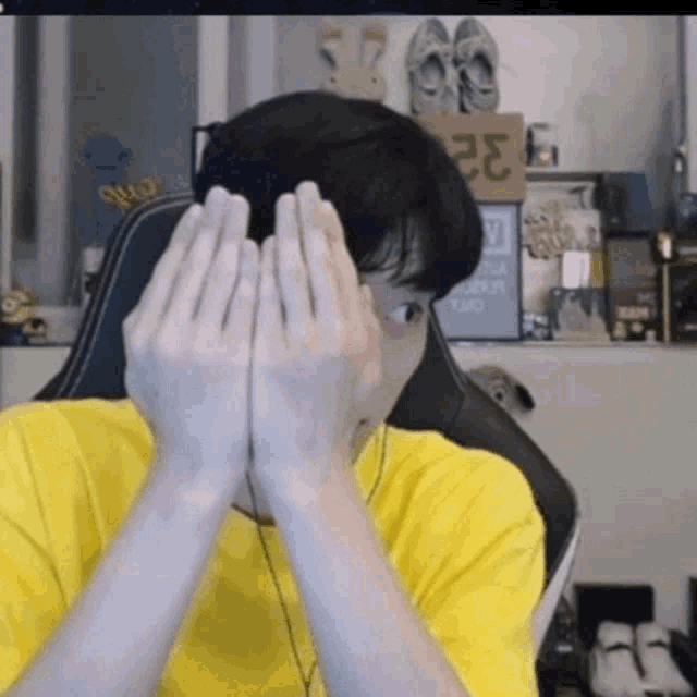 a man in a yellow shirt is covering his face with his hands in front of a sign that says 32