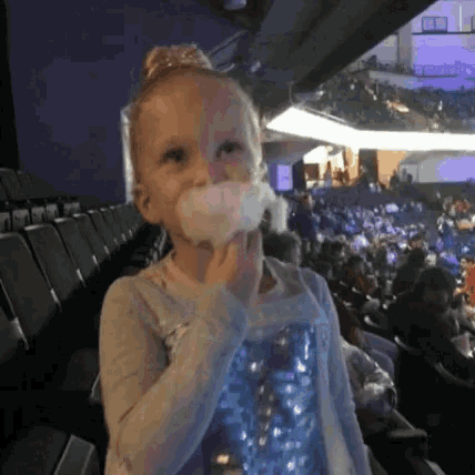 a little girl eating cotton candy in a crowded auditorium