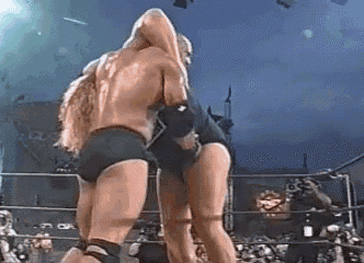 two men are wrestling in a wrestling ring with a crowd watching .