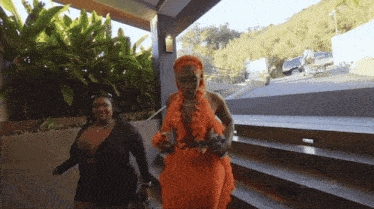 a woman in an orange dress is walking down some stairs