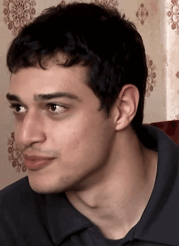 a close up of a man 's face with a gray shirt on