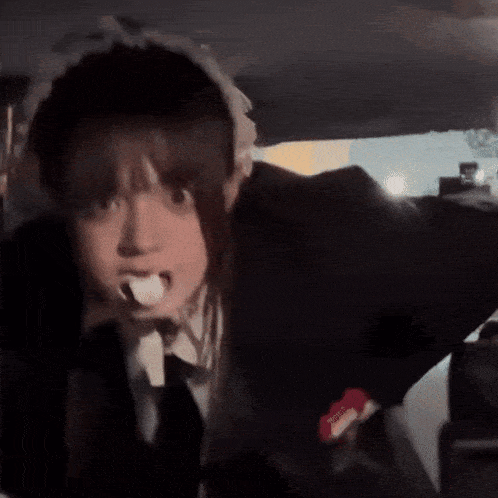 a girl in a maid costume is brushing her teeth in the back of a car