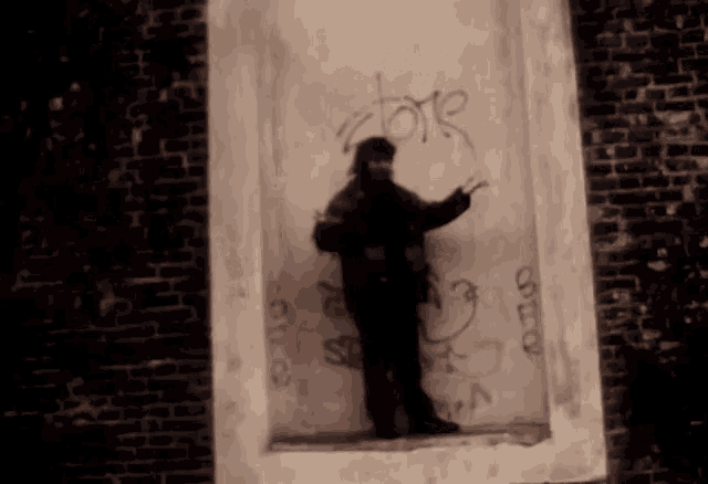 a man is standing in front of a wall with graffiti on it that says " love "