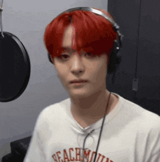 a young man with red hair is wearing headphones and a t-shirt that says beachmouth .