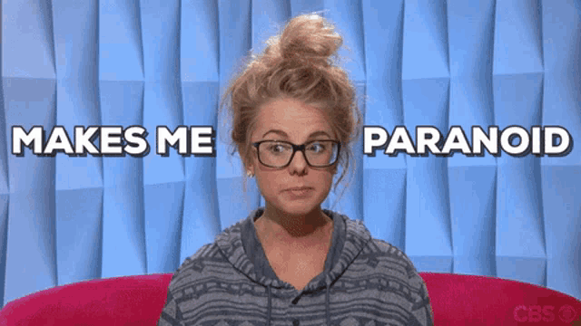 a woman wearing glasses is sitting in front of a wall that says makes me paranoid