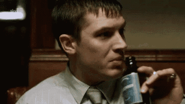 a man in a suit and tie is drinking from a bottle of beer .
