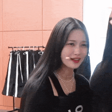 a woman with long black hair and a necklace that says o on it