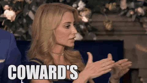 a woman is clapping her hands and the word coward 's is on her face .