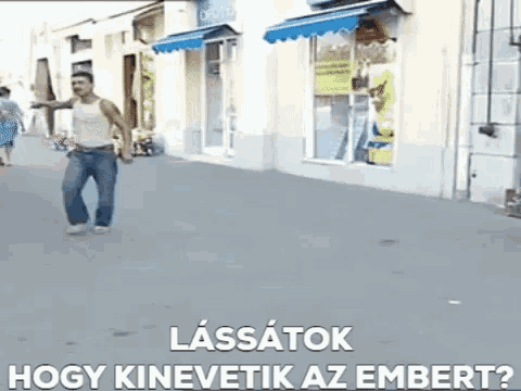 a man is walking down a sidewalk in front of a store with the words lassatok hogy kinevetik az embert