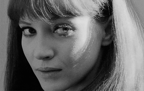 a black and white photo of a woman 's face with long hair and a fringe .