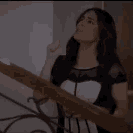 a woman in a black and white dress is standing on a staircase holding a railing .