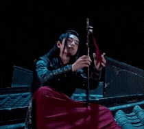 a man is sitting on a roof playing a flute in a dark room .