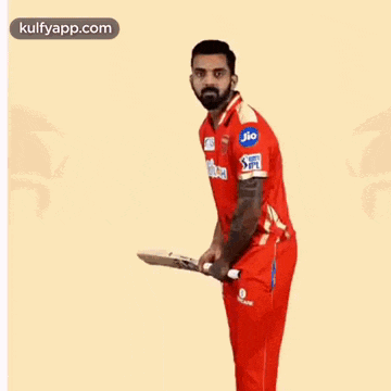 a man in a red shirt and red pants is holding a cricket bat in his hand .