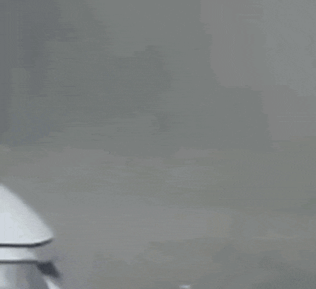 a police car with blue lights is driving down a street in the fog .