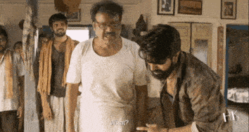 a group of men are standing in a room talking to each other and one of them is asking another man what .