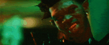 a close up of a person 's face in a dark room with a green background .