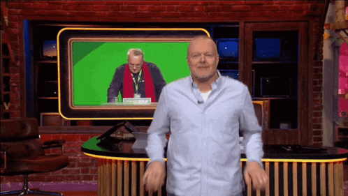 a man in a blue shirt stands in front of a green screen that says ' i 'm on now '