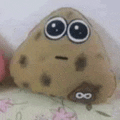 a stuffed potato with big eyes and a smiley face is sitting on top of a bed .