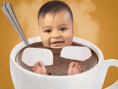 a baby 's face is in a cup of hot chocolate with marshmallows