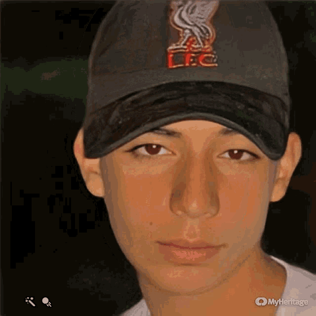 a young man wearing a liverpool baseball cap looks at the camera