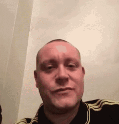 a man with a shaved head is wearing a black and yellow adidas shirt .