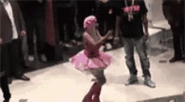 a woman in a pink tutu is dancing in front of a crowd .
