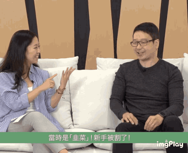 a man and a woman are sitting on a couch with chinese writing on the screen