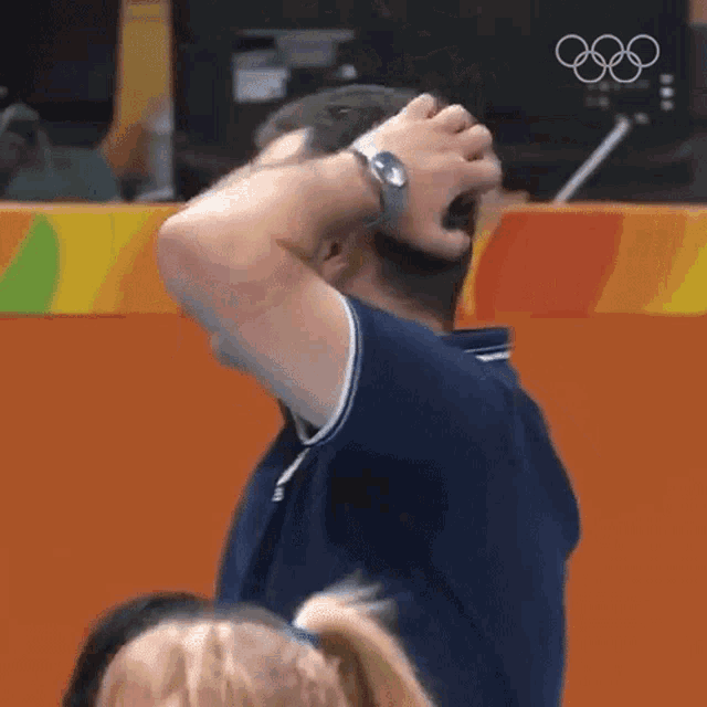 a man is holding his head in his hands while wearing a watch on his wrist .