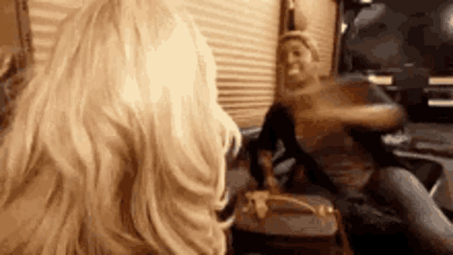 a woman is sitting in front of a mirror holding a purse and looking at herself .