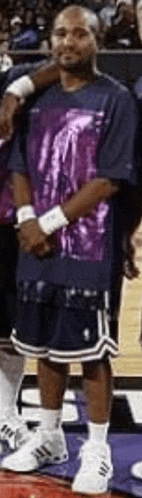 a man wearing a purple shirt and blue shorts is standing on a basketball court