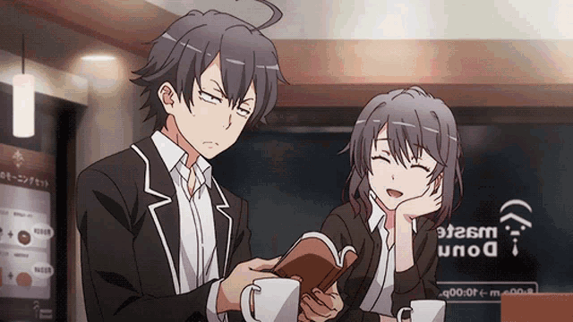 a man and a woman are sitting at a table in front of a sign that says ' don ' on it