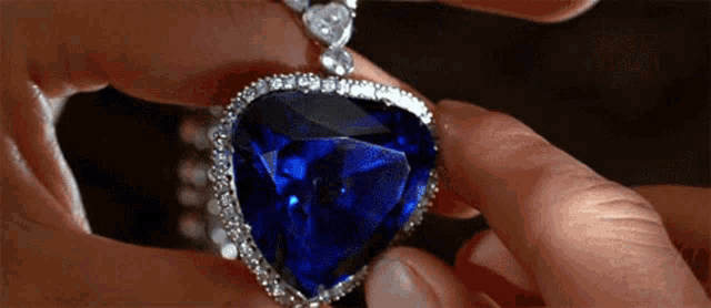 a close up of a person holding a heart shaped sapphire