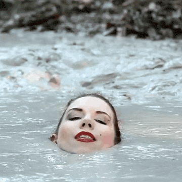 a woman with red lipstick is swimming in a body of water