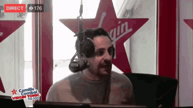 a man wearing headphones stands in front of a virgin sign