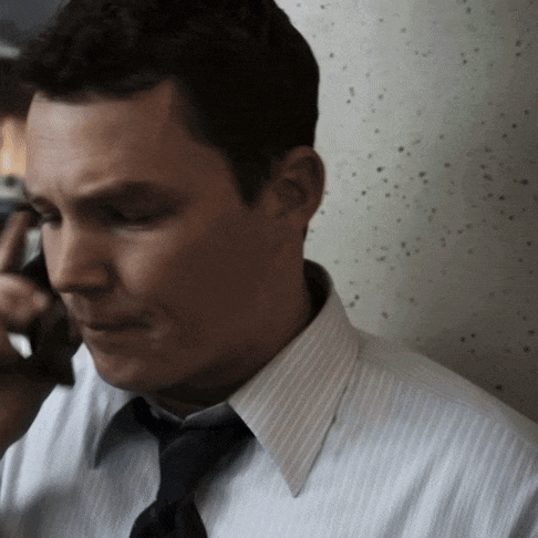 a man in a striped shirt and tie is talking on his cell phone
