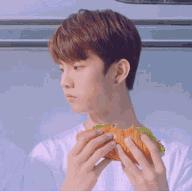 a young man is eating a sandwich with lettuce