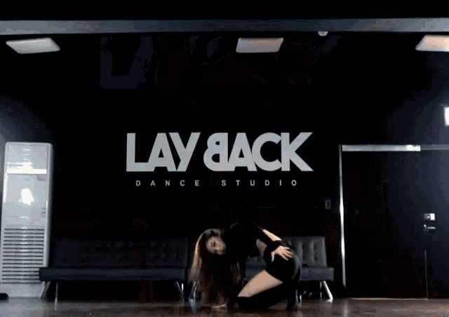 a woman dancing in front of a sign that says lay back