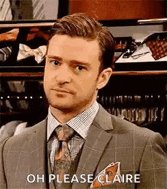 a man in a suit and tie is standing in front of a closet and making a face .