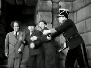 a group of men are standing next to each other and a police officer is holding a man .