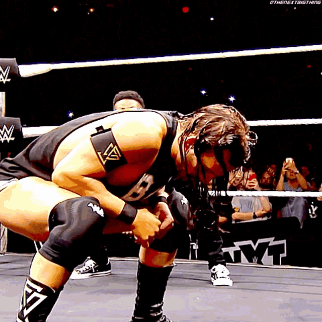 a wrestler is kneeling down in a wrestling ring while a crowd watches
