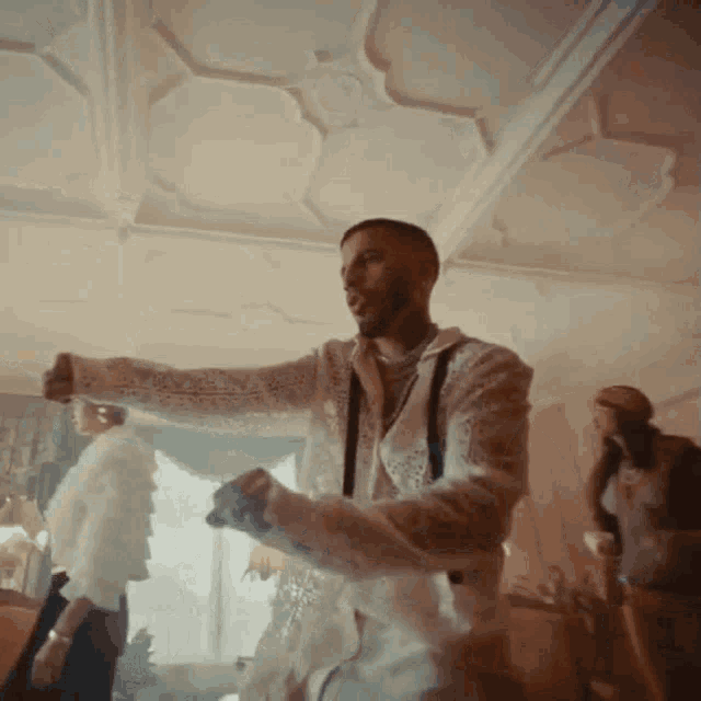 a man in a white shirt is dancing in a room with other people