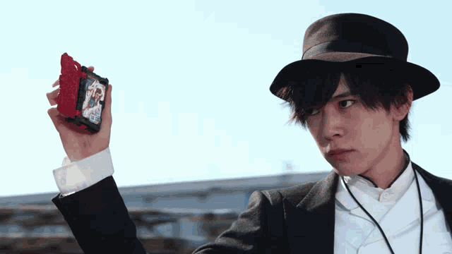 a man in a suit and hat holds a red object