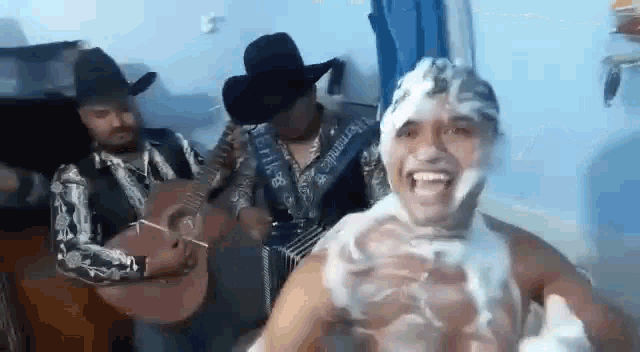 a man in a bathtub with soap on his face is playing a guitar and an accordion .